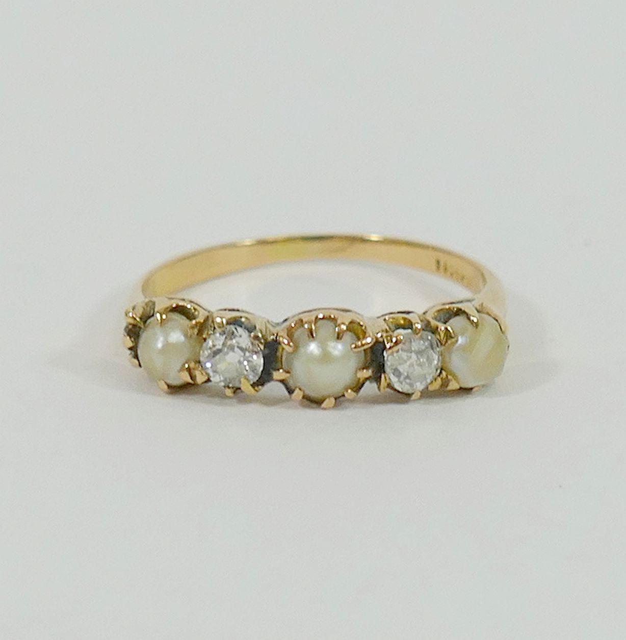 A yellow metal pearl and diamond five-stone ring, the two old cut diamonds approximately 0.