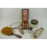 Three silver backed dressing table items comprised of a two brushes and a hand mirror,