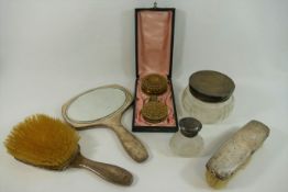 Three silver backed dressing table items comprised of a two brushes and a hand mirror,