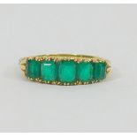 An Edwardian gold and emerald five stone carved half hoop ring,
