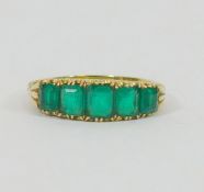 An Edwardian gold and emerald five stone carved half hoop ring,