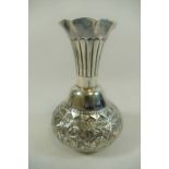A small silver coloured metal vase, the body with embossed decoration and flared rim,