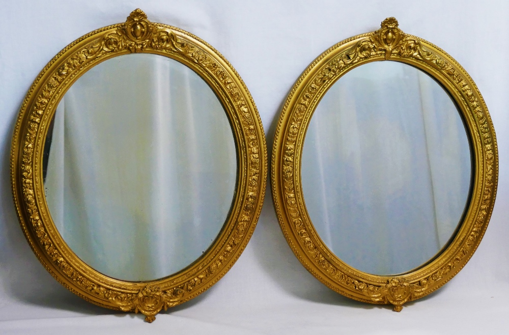 A pair of oval gilt framed mirrors, the