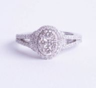 An 18ct white gold and oval diamond micro claw set cluster ring comprising 84 round brilliant cut