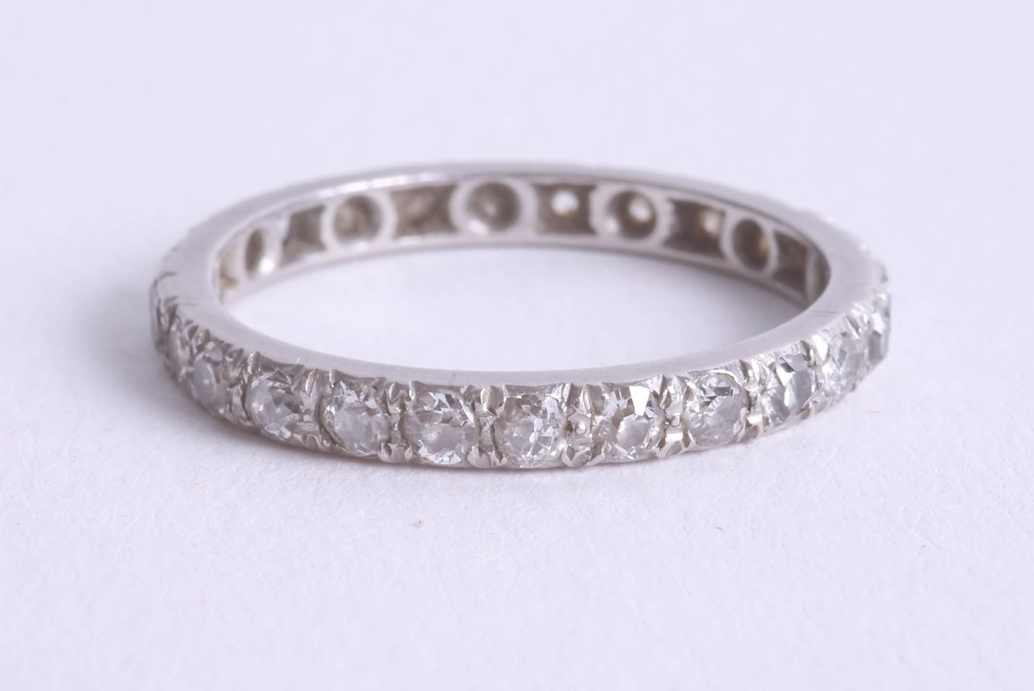 A full band eternity ring set in white metal (lacks two stones), size Q.