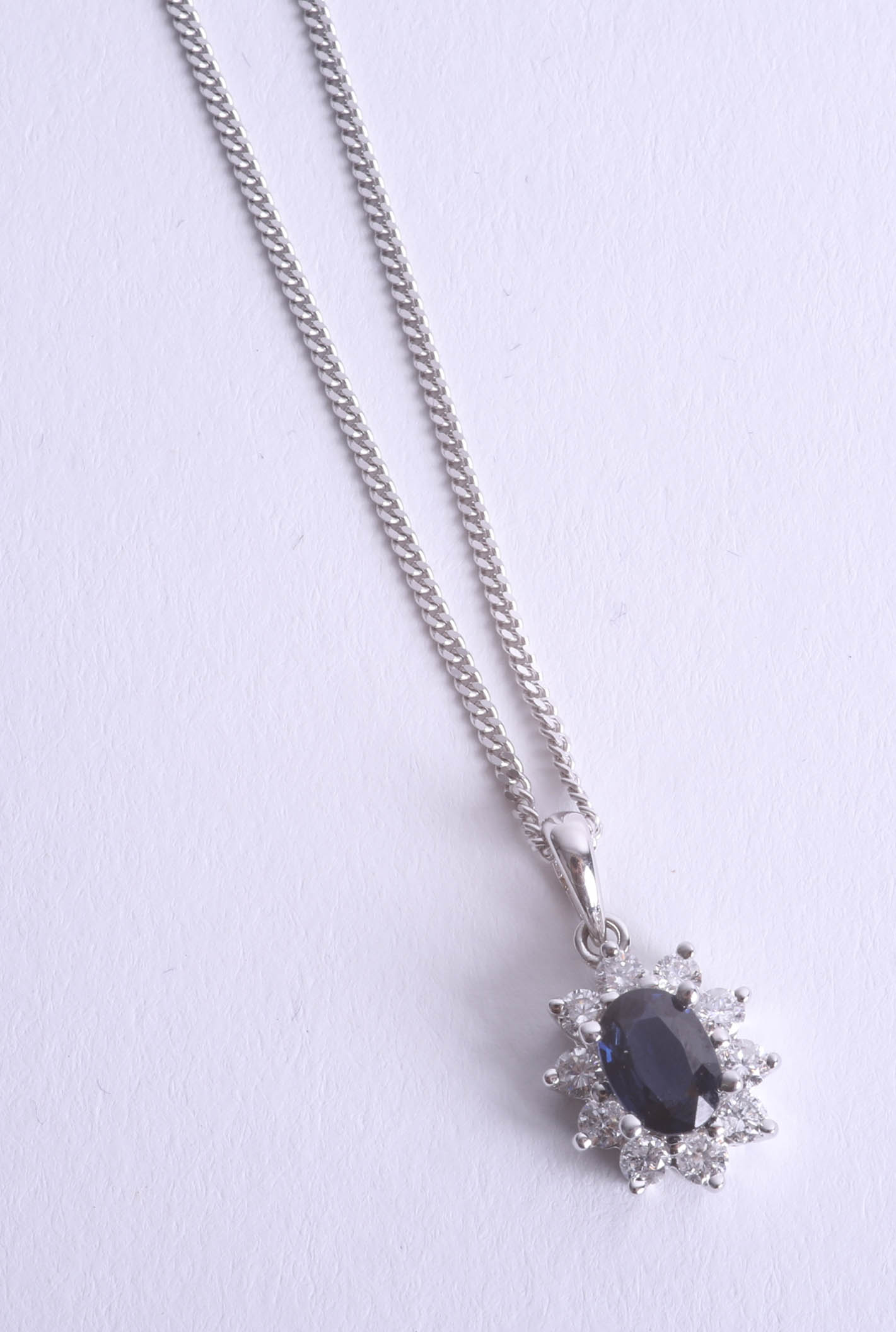 An 18ct white gold diamond and sapphire cluster pendant.