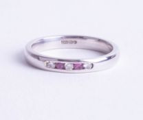 A 9ct white gold band ring set with diamond and pink sapphires, ring size K.