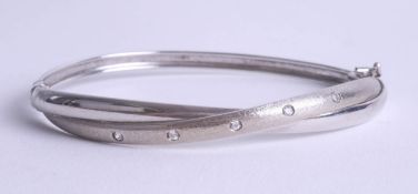 An contemporary 9ct white gold and diamond set bangle.