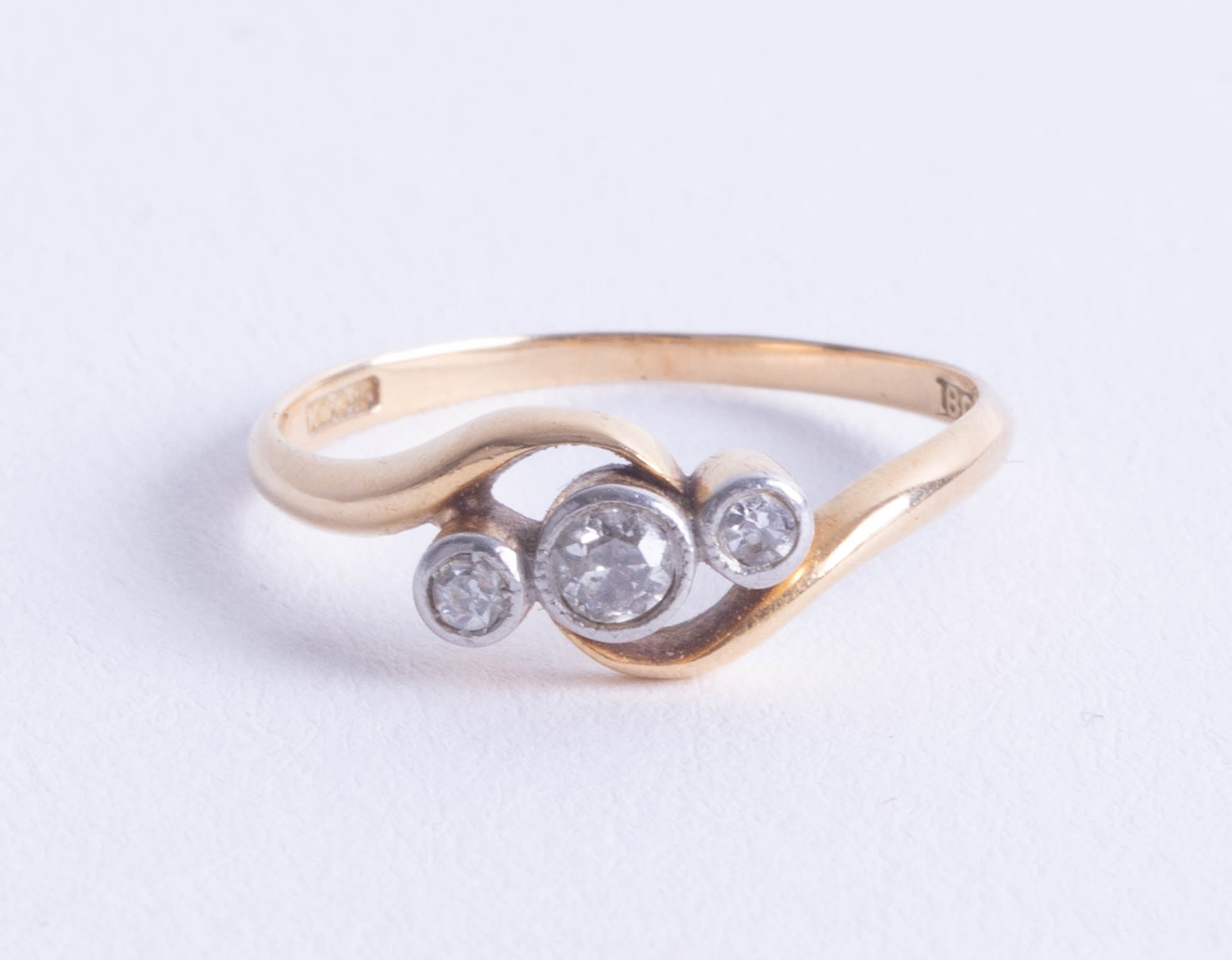 An 18ct diamond three stone ring rub over setting, size N.