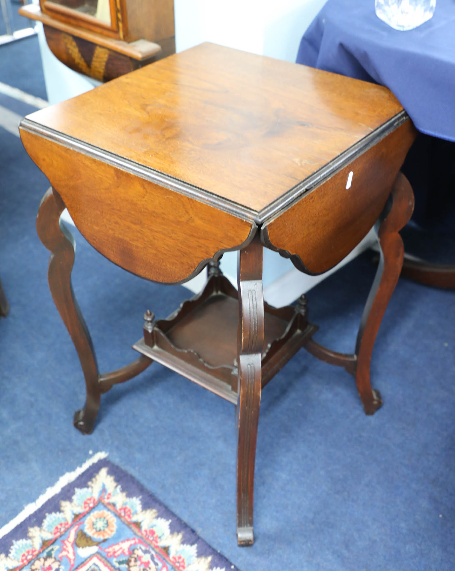 A mahogany drop flap games table with pull-out counter drawers with a lower tier and shaped legs.