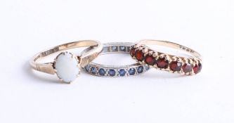 Three dress rings including, 9ct gold garnet ring, 9ct opal ring and a white metal sapphire full