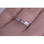 An 18ct white gold and three stone diamond ring set with princess cut diamonds, size I.