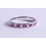 An 18ct white gold ruby and diamond set half band eternity ring, size O.