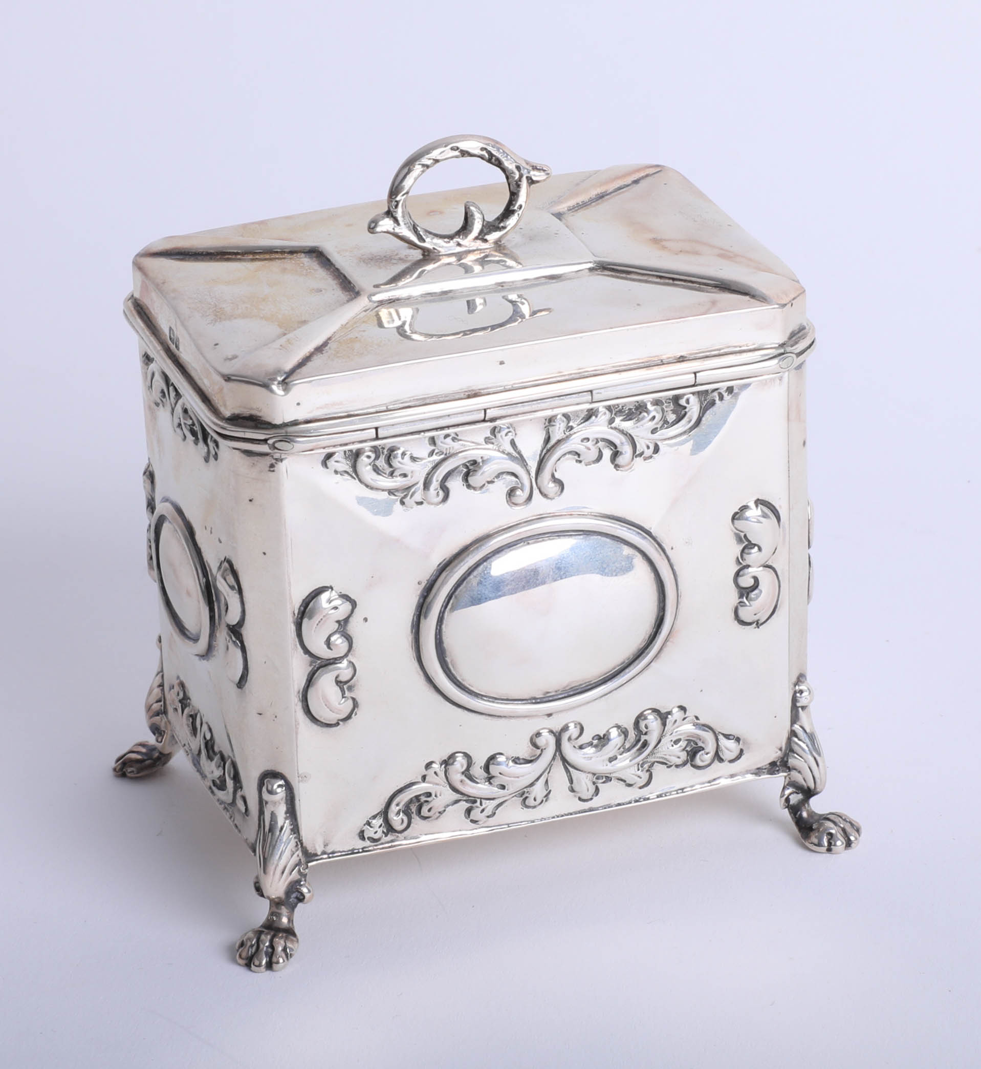 An Edwardian silver tea caddy with embossed decoration on lion paw feet, 1906, height 11cm, makers