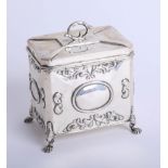 An Edwardian silver tea caddy with embossed decoration on lion paw feet, 1906, height 11cm, makers