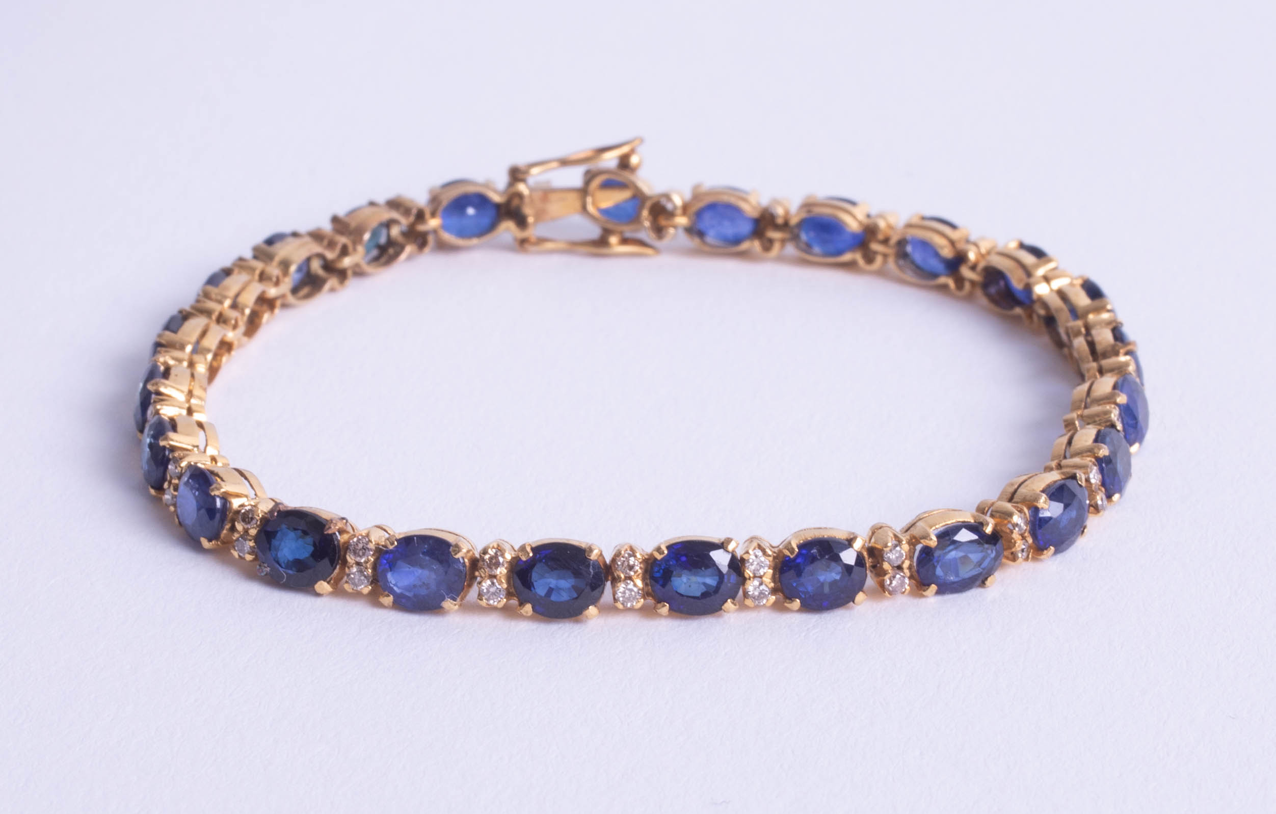 A sapphire and diamond line bracelet, set in yellow metal possibly 18ct, not hallmarked, length