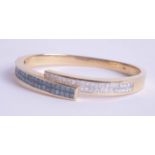 An 18k yellow gold bangle set with blue and white diamonds, approx 41.60g, purchased in 2007 for £