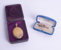 An Edwardian 15ct and ruby set gold brooch together with a memoriam locket, both cased.