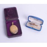 An Edwardian 15ct and ruby set gold brooch together with a memoriam locket, both cased.