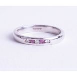 A 9ct white gold band ring set with diamond and pink sapphires, ring size K.