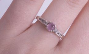 A 14ct white gold ring set with a pink sapphire, size N.