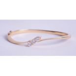 An 18ct three stone diamond cross over twist design bangle, approximately 63mm x 50mm, plain solid