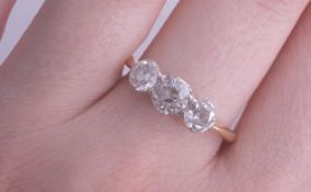 An 18ct three stone diamond ring, the centre stone approximately .50 carats, size N, being sold to
