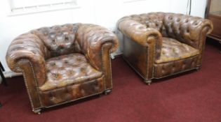 A pair of leather upholstered and button back chesterfield style club armchairs on small brass