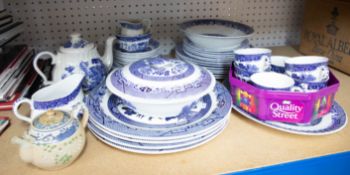 A collection of blue and white willow patterned dinnerware's together with an oriental teapot.