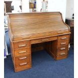 A large early 20th century oak roll top desk, the tambour front enclosing a fitted interior of