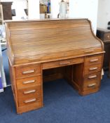 A large early 20th century oak roll top desk, the tambour front enclosing a fitted interior of