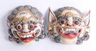 A pair of carved wood Asian face masks.