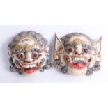 A pair of carved wood Asian face masks.