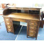 An early 20th century oak roll top desk, the tambour front enclosing various pigeon holes, over a
