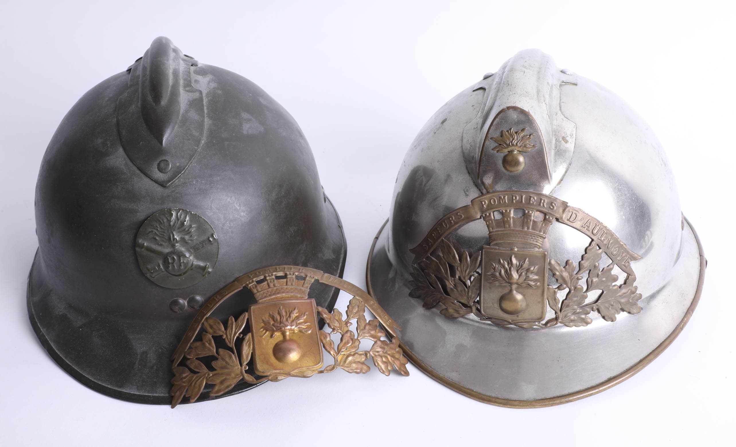 A French fireman's helmet, the crest marked Sapeurs Pompiers D'aulnoye and another helmet, marked