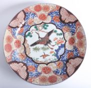 A fine and large antique Japanese charger, decorated with cranes among pine trees within a border of