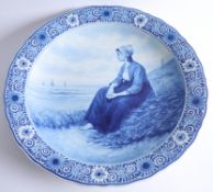A Delft blue and white charger by Thooft and Labouchere, depicting a Dutch girl sitting on the