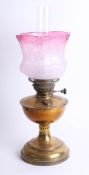 An oil lamp with cranberry shade, height 55cm.