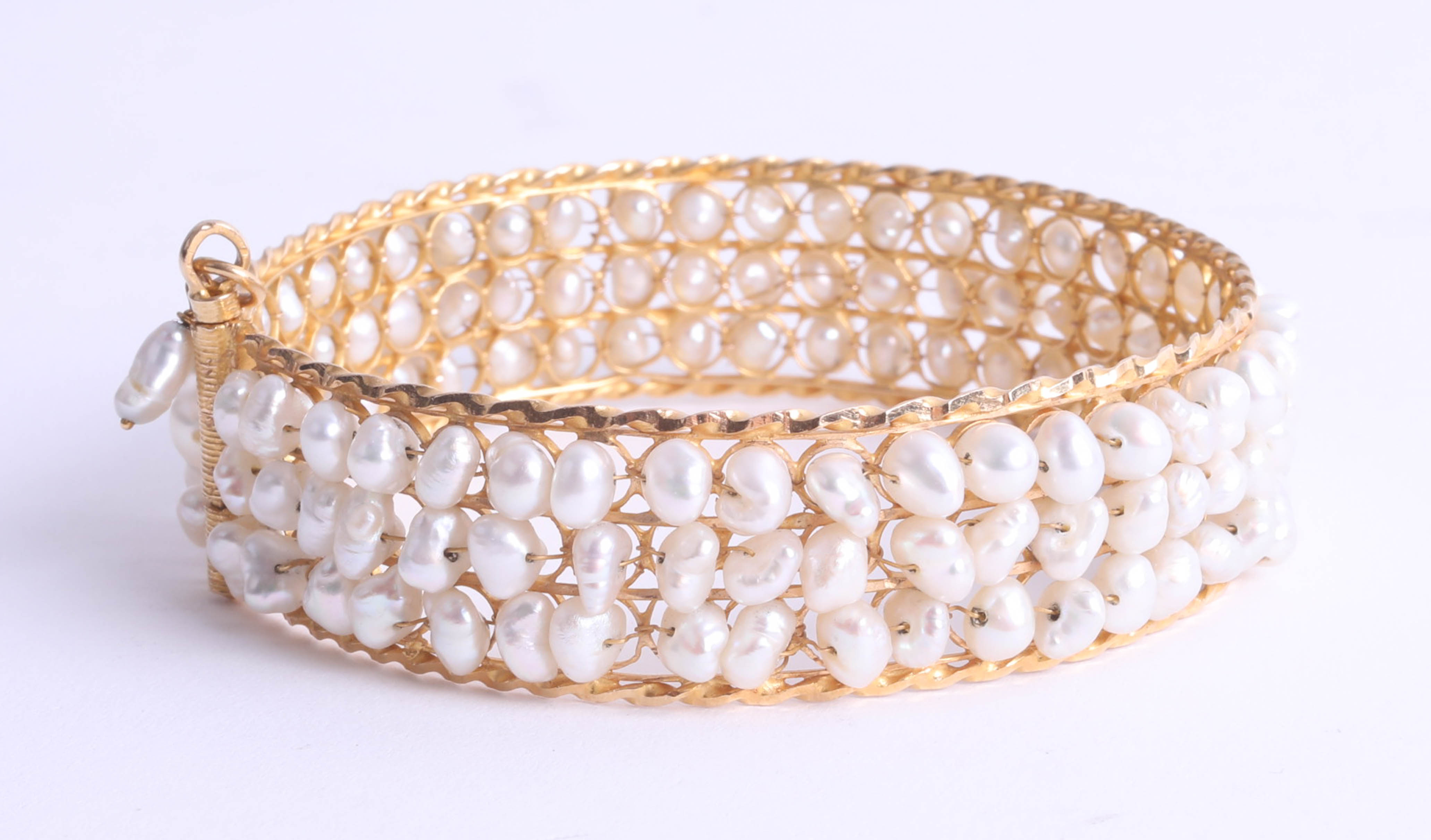 A middle eastern high carat yellow gold bangle (probably 18ct) set with freshwater pearls,