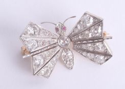 A fine diamond butterfly brooch, with spring wings and ruby glass eyes.