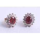 A pair of modern ruby and diamond cluster earrings, set in white metal with yellow screw backs.