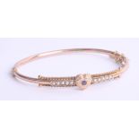 An Edwardian pearl and sapphire gold bangle with heart design.