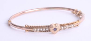 An Edwardian pearl and sapphire gold bangle with heart design.