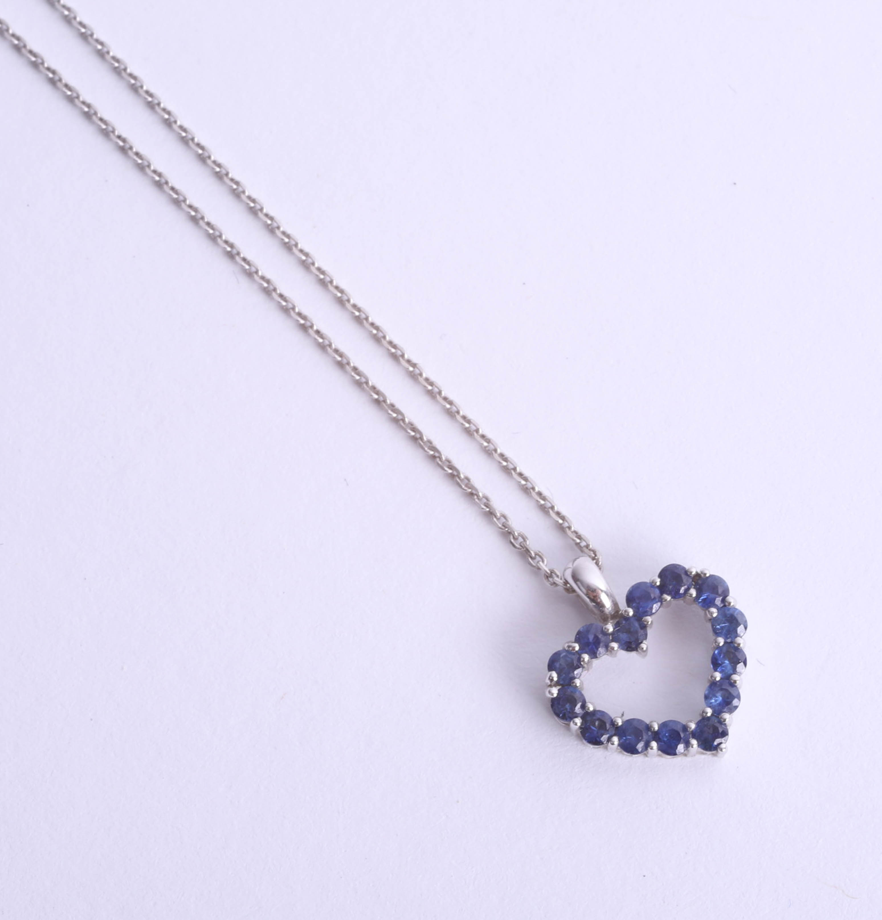 An 18ct white gold heart-shaped pendant, set with blue stone (sapphire?) on a fine chain.