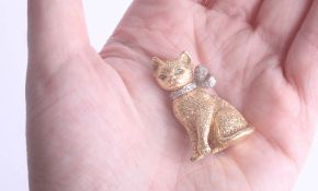 An 18ct gold cat brooch with emerald eyes and a diamond bow approx. 35 x 22mm, 21.40g.