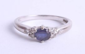 An 18ct white gold ring set with a central sapphire and six small diamonds, size K.