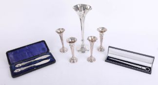 A weighted silver single flute, height 25cm, together with a group of four smaller silver flutes and