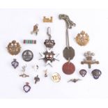 A collection of various badges, including some military cap badges, an enamelled pendant marked