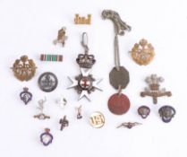 A collection of various badges, including some military cap badges, an enamelled pendant marked