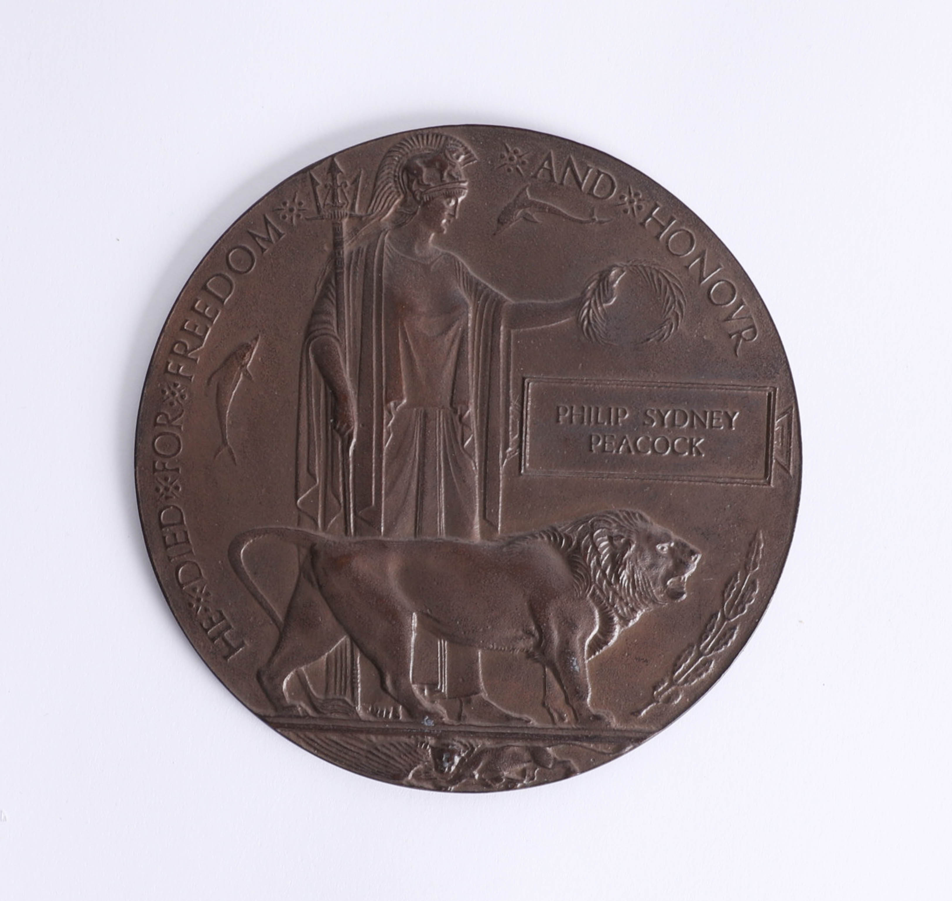 A Great War bronze 'death plaque' awarded to Phillip Sydney Peacock with card envelope.